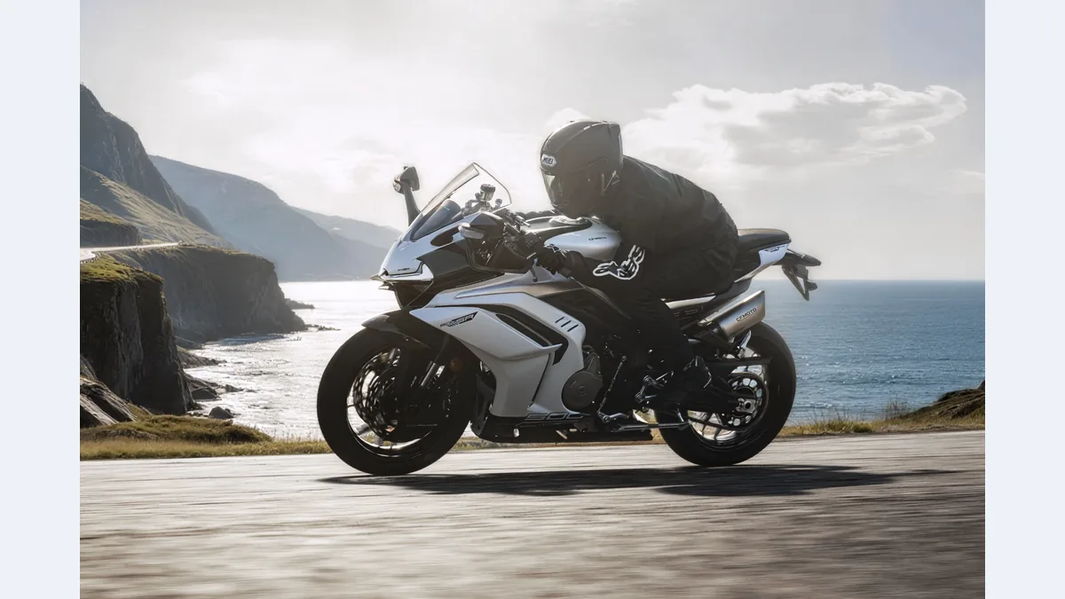 CFMOTO 500SR grise et blanche roulant sur une route en bord de mer