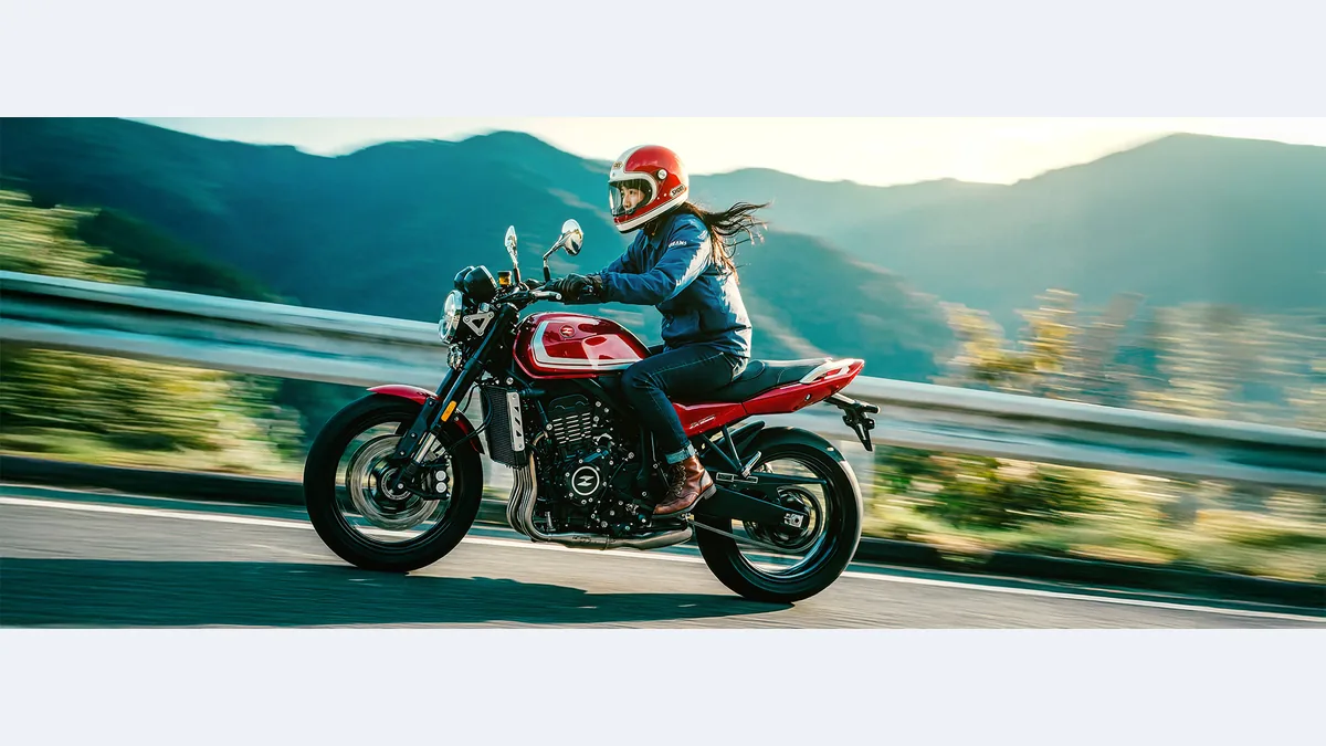 Motarde au guidon d'une ZXMOTO 500F rouge sur une route de montagne